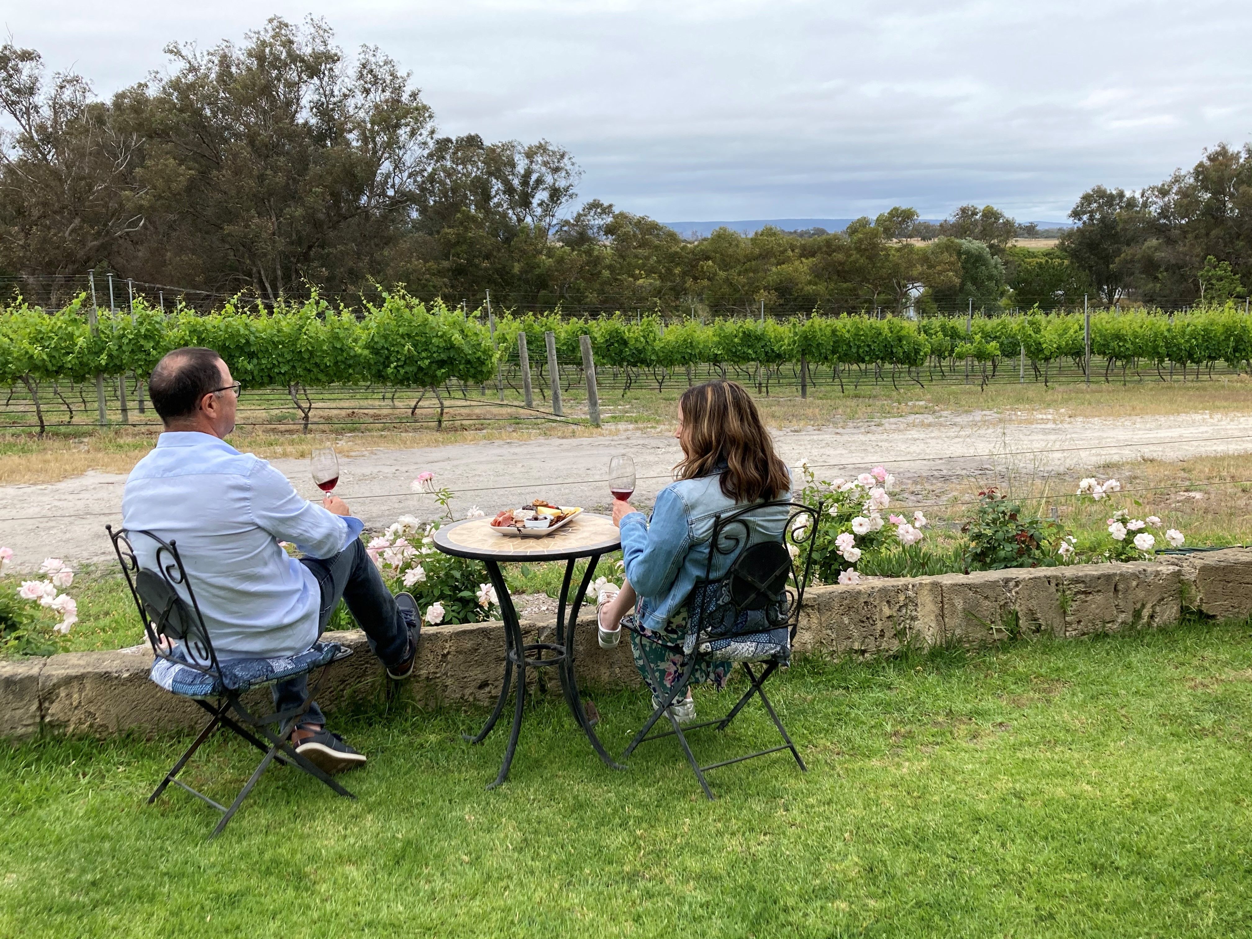 A man and woman sitting on the garden enjoying the view of the vineyard 